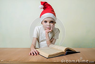 Ð¡ute girl in Santa Claus hat eat cookies. Stock Photo